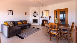 Ein modernes Wohnzimmer mit einer Couch, einem Esstisch, Stühlen und einem Kamin.