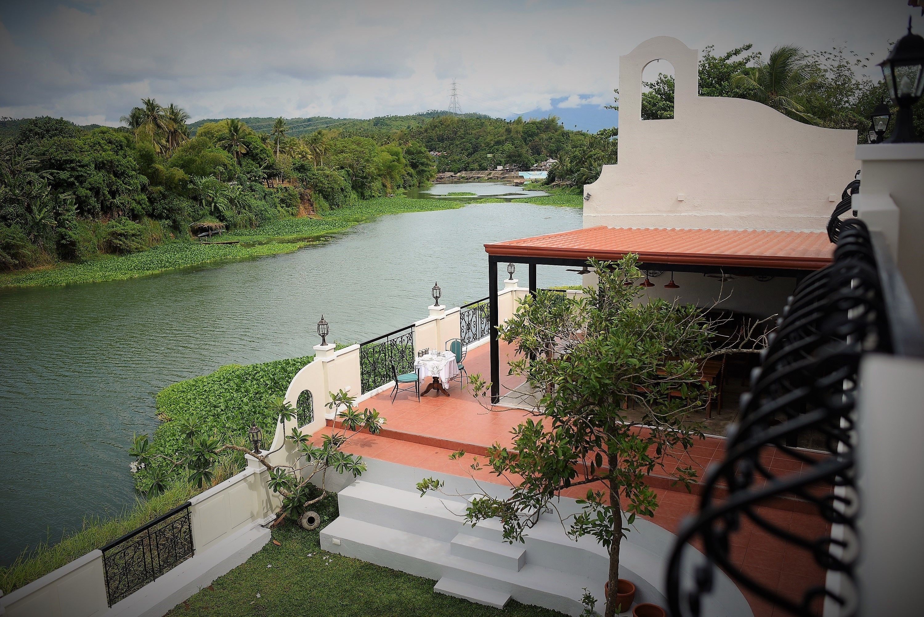 A riverside view from a balcony with steps leading down to a terrace.