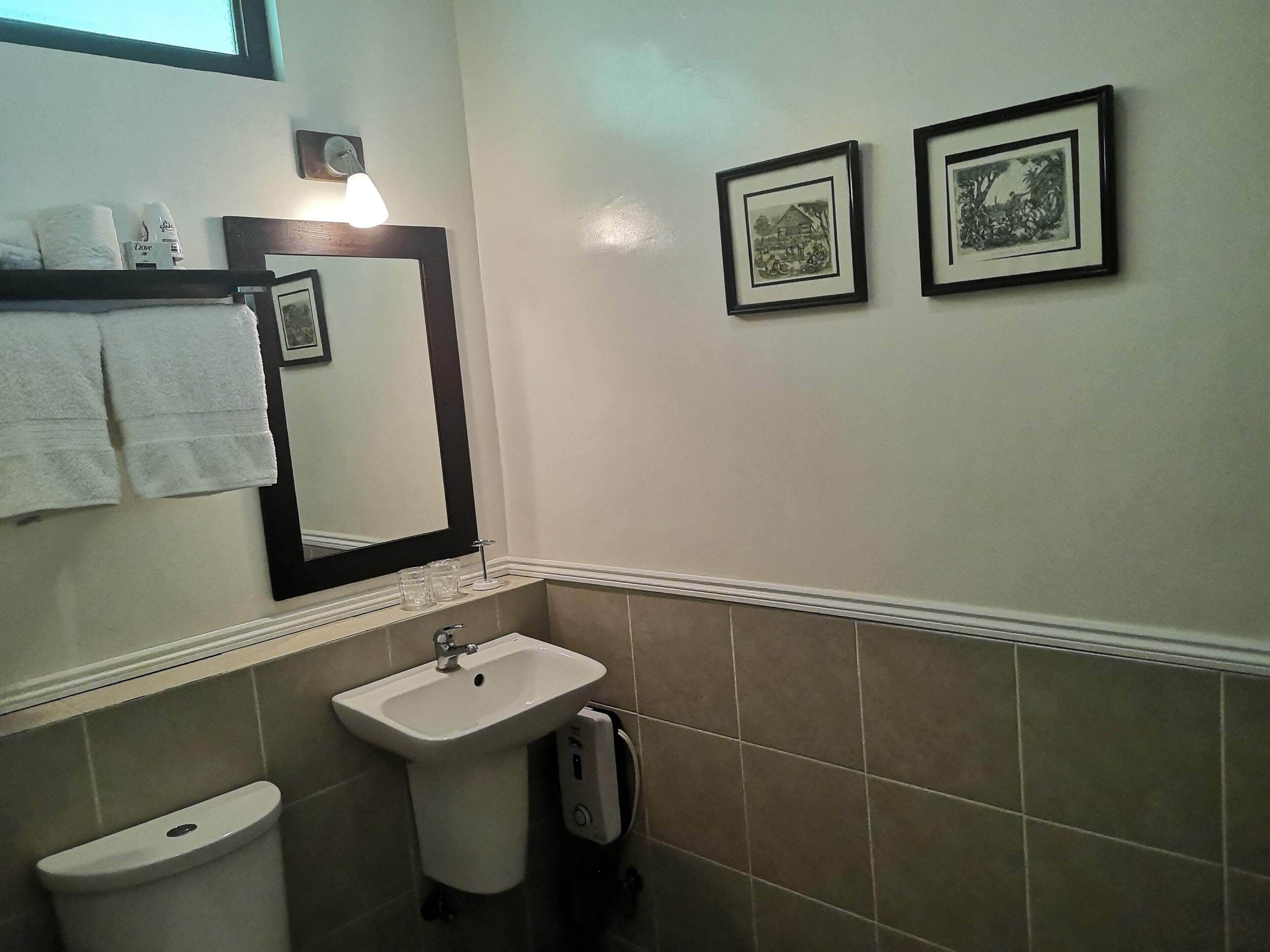 Un baño con lavamanos, inodoro y dos cuadros en la pared.