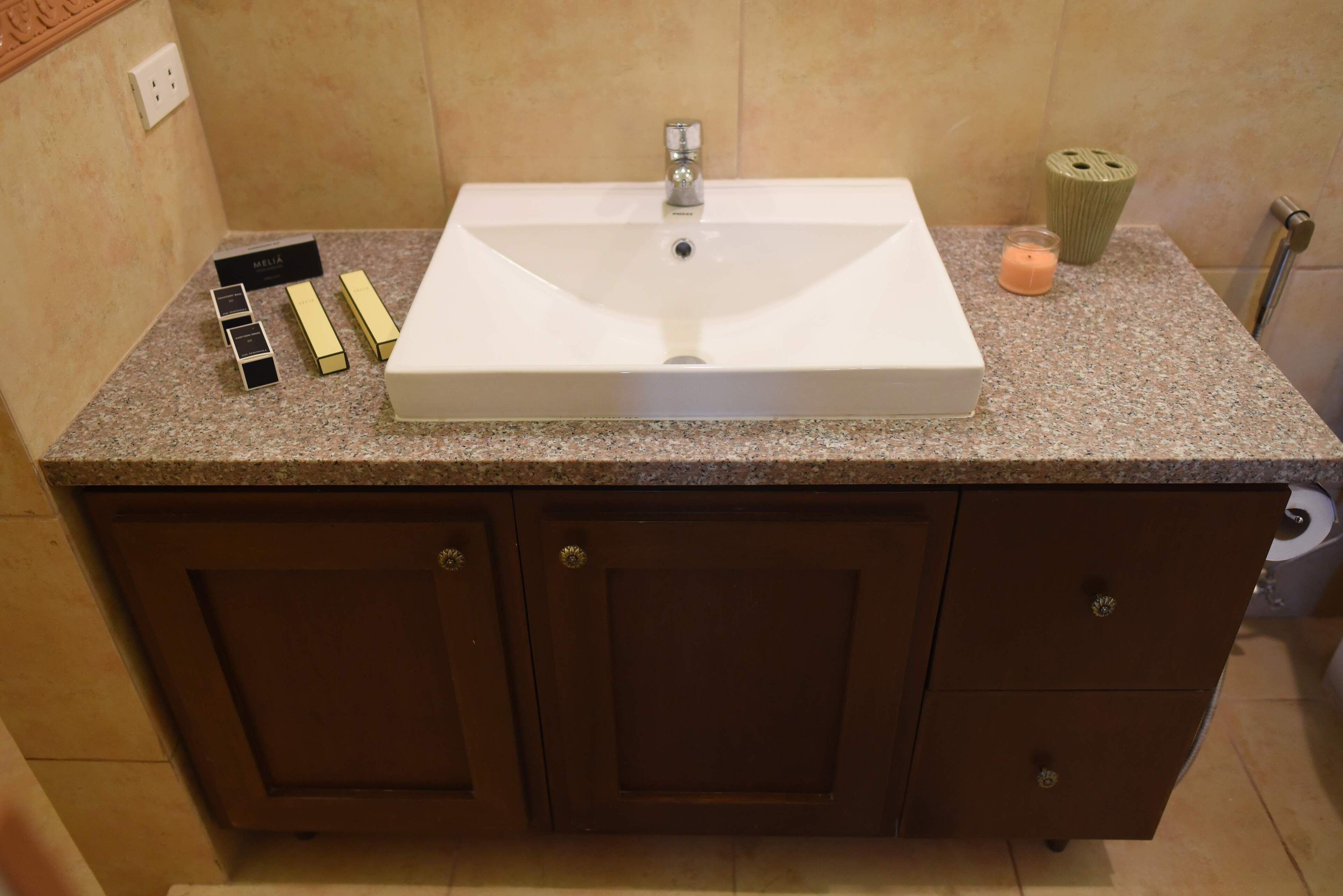A bathroom with a white sink, granite countertop, and wooden cabinets.