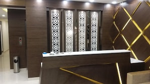 A reception desk with a modern design, featuring a wooden finish and geometric patterns. - Sand Silver Business Hotel (Chennai)