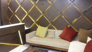 A modern interior with a wooden accent wall, a sofa with cushions, and a wooden reception desk. - Sand Silver Business Hotel (Chennai)