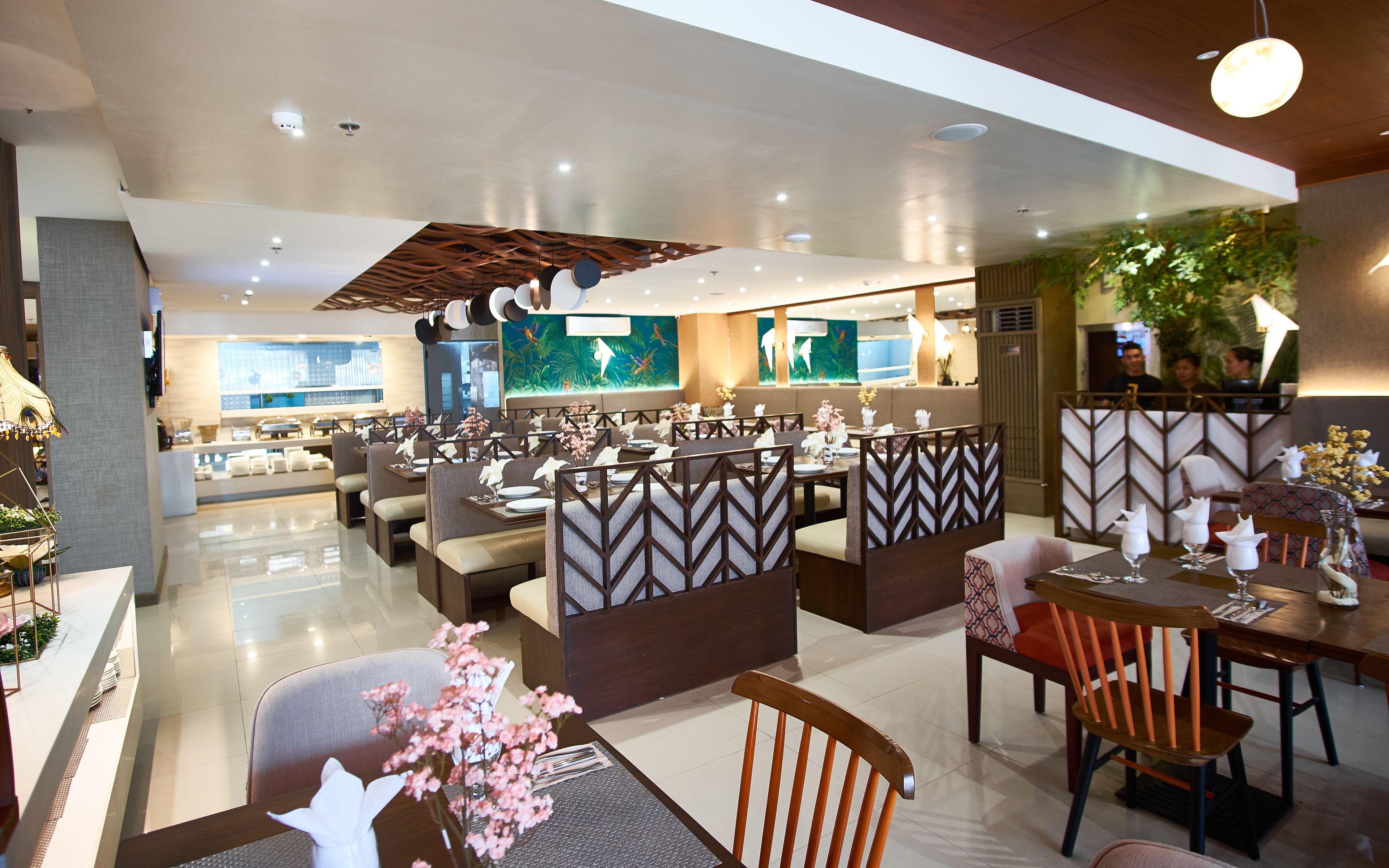Un restaurante moderno con un ambiente limpio y espacioso, que ofrece mesas y cabinas con centros de mesa florales.