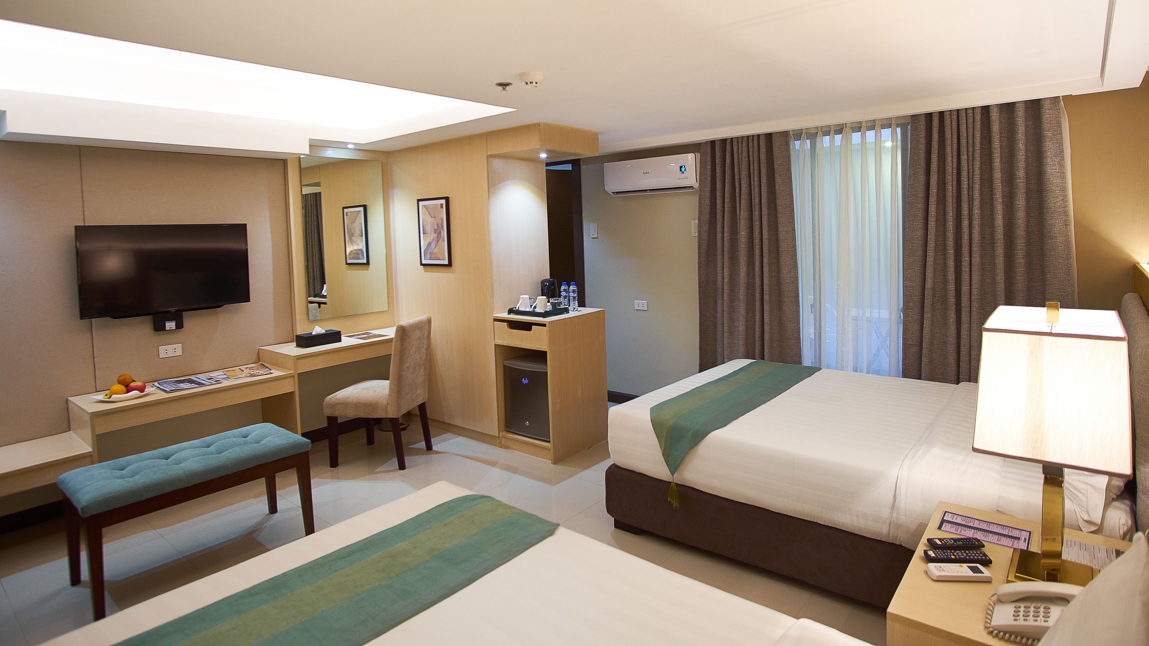 A hotel room with a bed, desk, chair, and a TV.