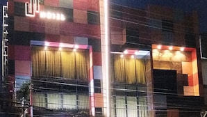 A hotel with a modern facade, large windows, and a visible entrance with a car parked outside. - J7 Hotel Iloilo (Iloilo)