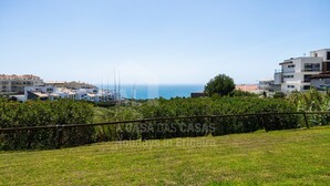 Ett bostadsområde vid kusten med moderna byggnader, fri utsikt över havet och en grönskande förgrund.