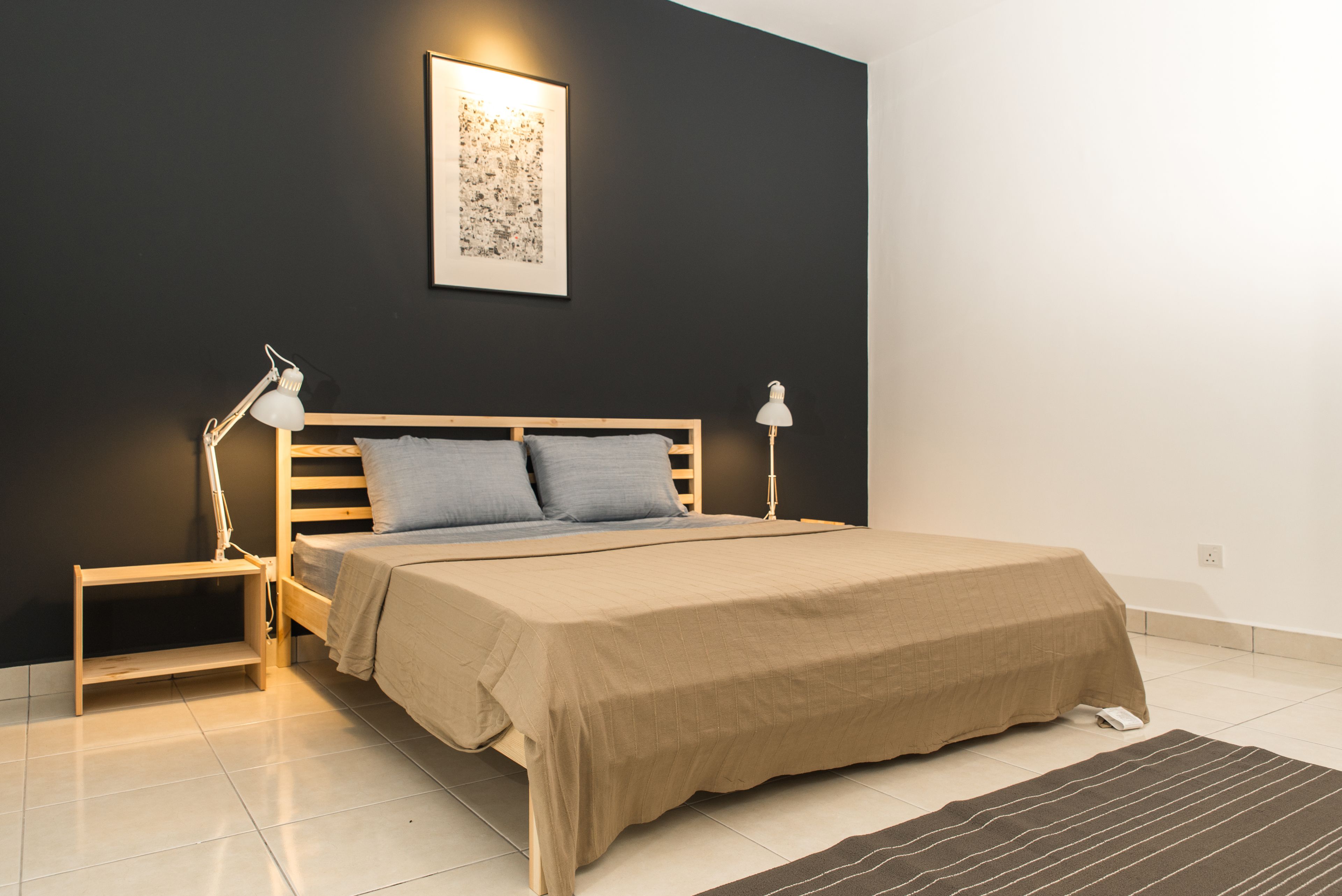 A bedroom with a bed, bedside lamps, a nightstand, a wall-mounted artwork, and a floor lamp.