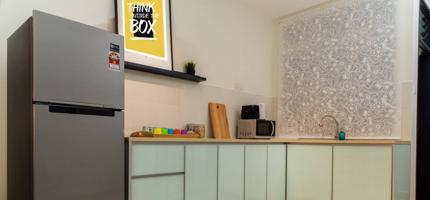 A kitchen with a stainless steel refrigerator, a microwave, and a sink. There is a shelf with a plant and a sign that says "THINK OUTSIDE THE BOX".