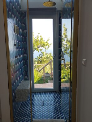 Un baño con piso estampado, una puerta que da al exterior y un pequeño banco.
