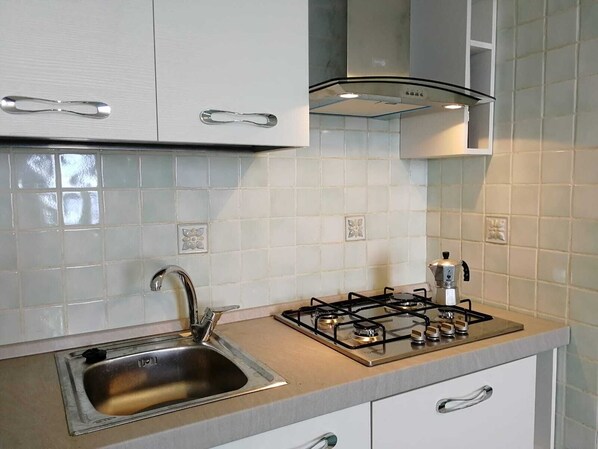 A modern kitchen with white cabinets, a stainless steel sink, a gas stove, and a range hood. - New Boutique Villa Donna Antonia near Amalfy and Positano sea view free wifi (conca dei marini)