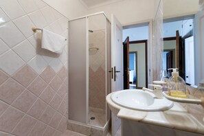 Experience a contemporary bathroom with a walk-in shower, sink, and large mirror.