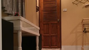 Un pasillo con una puerta de madera, un banco blanco y una alfombra roja.