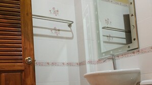 Un baño con puerta de madera, un inodoro, un lavabo y un cubo de basura.