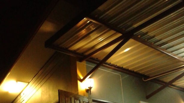 Una casa con puerta de madera, ventana y techo de metal.