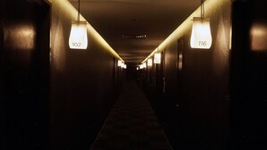 A long, dimly lit hallway with numbered doors, suggesting a hotel or similar accommodation. - Urban H Hotel (George Town)