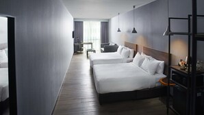 A hotel room with two beds, a desk, a chair, a TV, and a wardrobe. - Urban H Hotel (George Town)