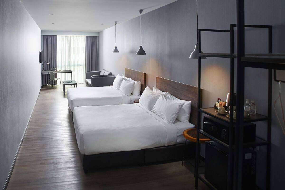 A hotel room with two beds, a desk, a chair, a TV, and a wardrobe.