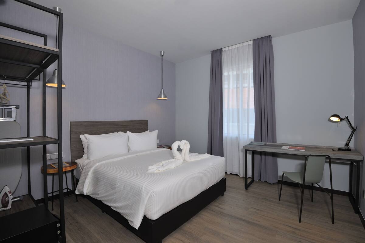 A hotel room with a bed, a desk, and a chair.