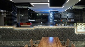 A modern bar area with a geometric patterned counter, a menu board, and seating. - Urban H Hotel (George Town)