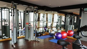 A gym with exercise equipment, mirrors, and exercise balls. - Urban H Hotel (George Town)