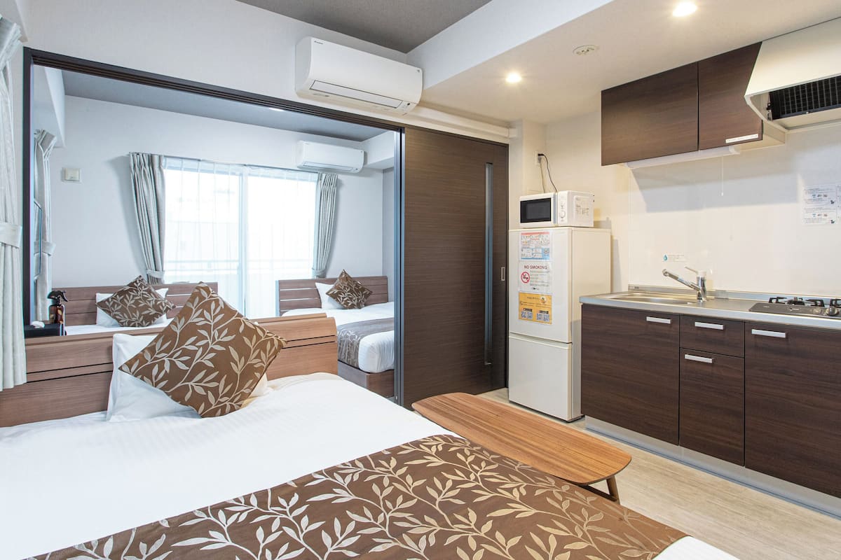 Een hotelkamer met een bed, een bankje, een kitchenette en een badkamer.