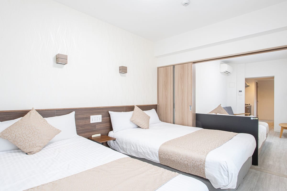 Een hotelkamer met twee bedden, een houten hoofdeinde, een spiegel en een klein tafeltje.