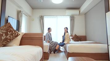 Quarto de hotel com duas camas de solteiro, uma secretária e uma televisão.