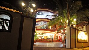 A hotel entrance with a Santa Claus decoration, palm trees, and a well-lit facade. - Raposo Holiday Resort (Vagator)
