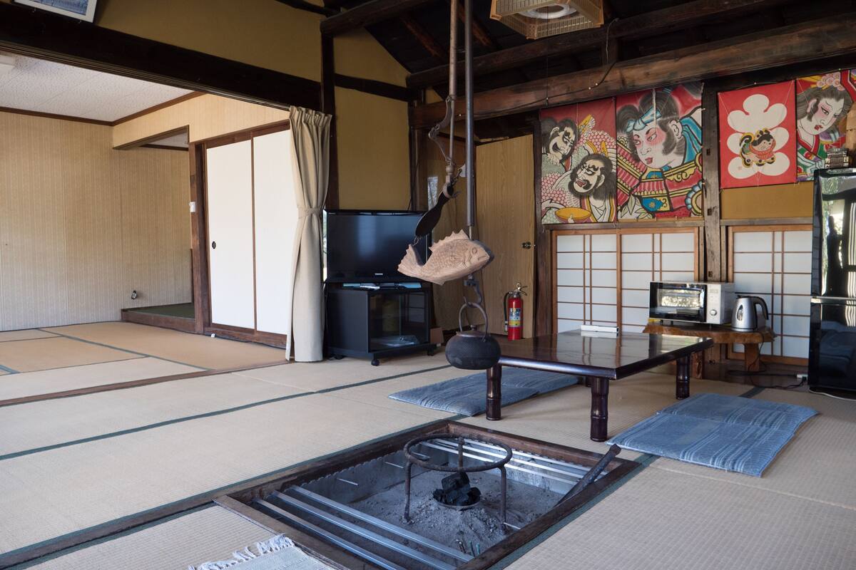 Ett traditionellt japanskt rum med tatamimattor på golvet, en tv, en vattenkokare och en öppen spis.