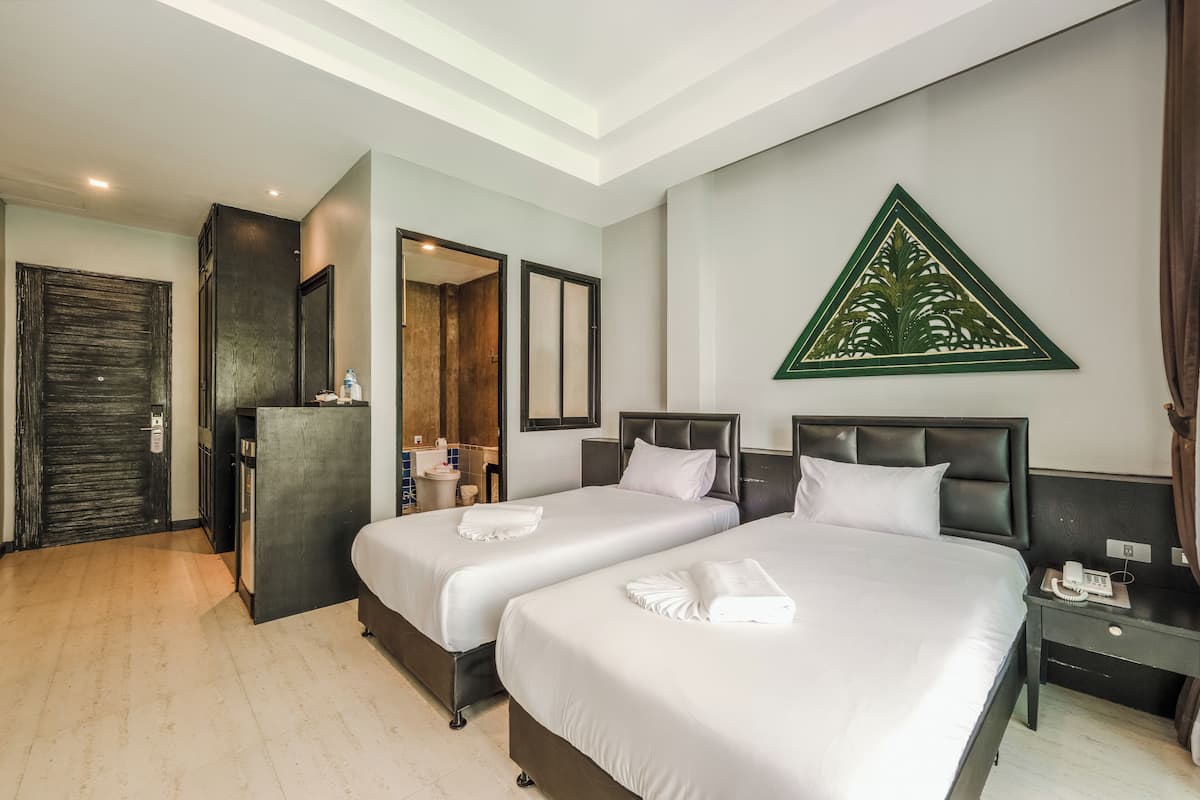Una habitación de hotel con dos camas, un espejo, un teléfono y un adorno en la pared.