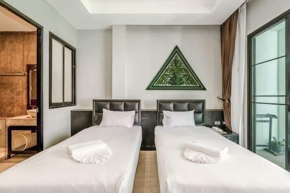 Una habitación de hotel con dos camas, un ventanal grande y un adorno verde en la pared.