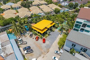 Vista aérea de una zona residencial con varias casas, un edificio de techo amarillo y coches aparcados.