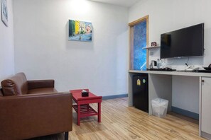 Um espaço compacto com cozinha compacta, televisão, sofá e mesa pequena.