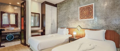 A hotel room with two beds, a bathroom with a sink and mirror, and a decorative wall piece.