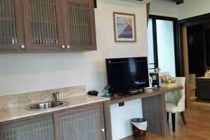 A modern kitchen with a built-in TV, a sink, and wooden cabinets. - Coco Retreat Phuket Resort and Spa Sha+ (Chalong)