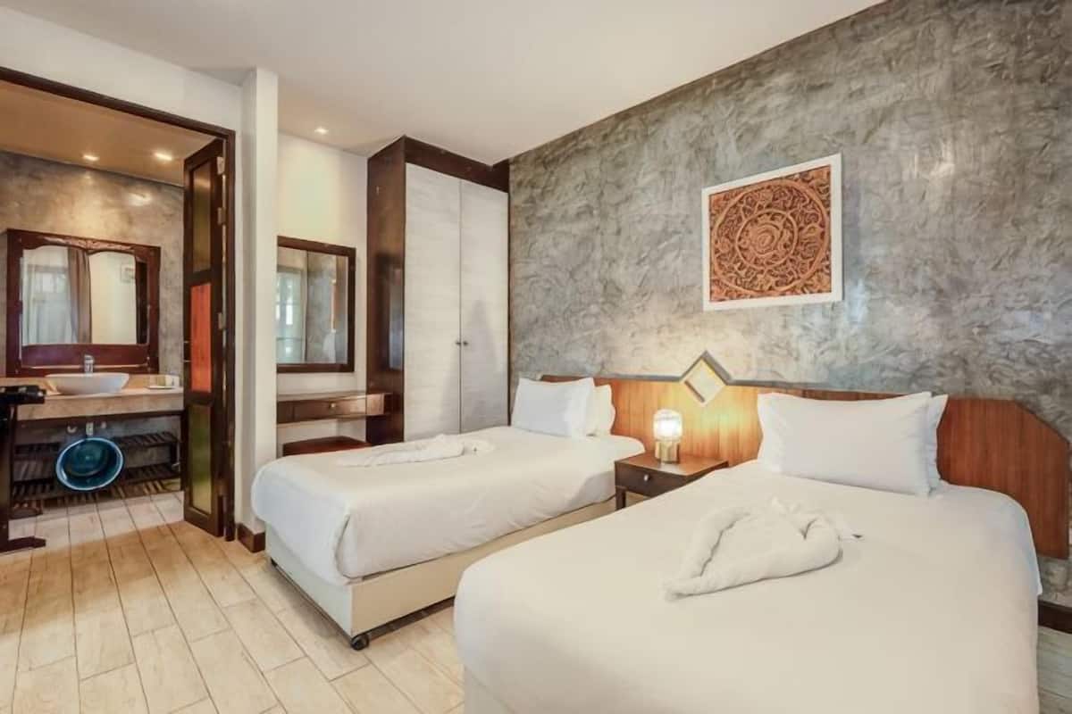 Habitación de hotel con dos camas, un baño con lavabo y un adorno en la pared.