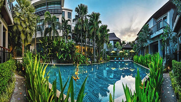 A swimming pool surrounded by lush greenery and modern buildings. - Coco Retreat Phuket Resort and Spa Sha+ (Chalong)