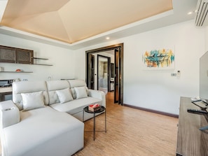 Ein modernes Wohnzimmer mit einem Ecksofa, einem kleinen Couchtisch und einem Gemälde an der Wand.