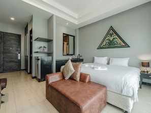 Ein Hotelzimmer mit einem Bett, einem braunen Ledersofa, einem Schreibtisch mit Stuhl, einem Spiegel und einem Wanddekor.