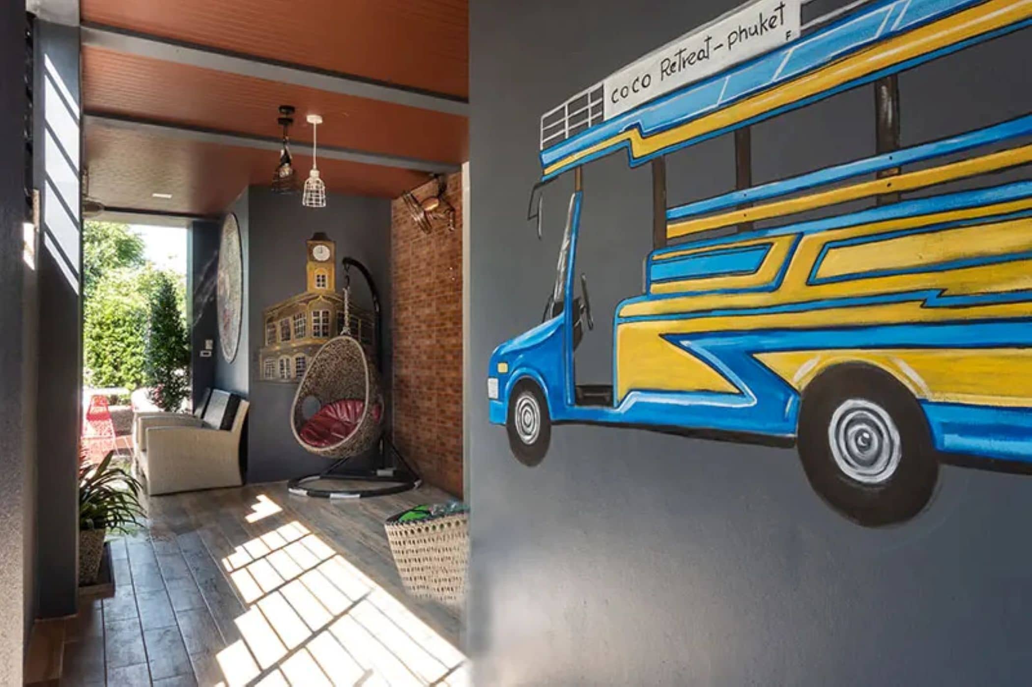 A room with a mural of a blue and yellow bus, a hanging light fixture, and a brick wall.