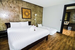 A hotel room with a large bed, a smaller bed, a wall with a decorative pattern, a floor lamp, and a wooden floor. - Coco Retreat Phuket Resort and Spa Sha+ (Chalong)