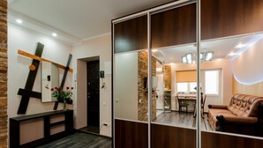 A modern interior with a wooden bench, a mirror, and a sliding door leading to a dining area. - CityApartments Kyiv Railway Station (Kyiv)