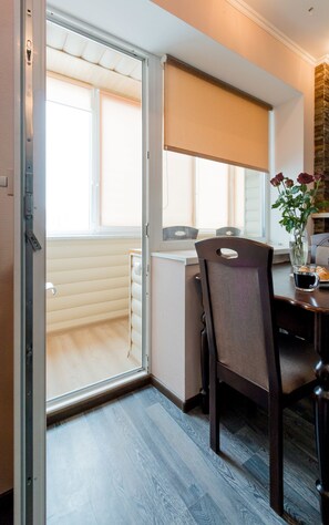 Et moderne køkken med en skydedør til en balkon, et spiseområde med et bord og stole, samt en vase med blomster på bordet.
