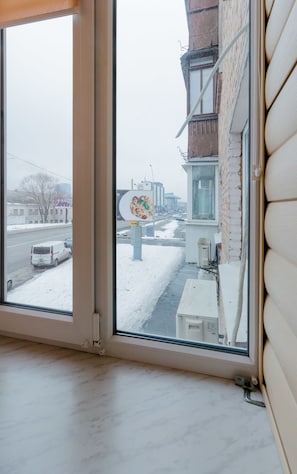 Et værelse med et stort vindue der kigger ud på en sneklædt gade og bygninger.