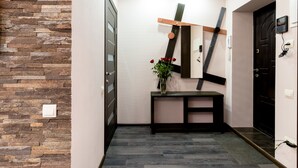 A hallway with a stone wall, a wooden bench, a vase with flowers, and a door. - CityApartments Kyiv Railway Station (Kyiv)