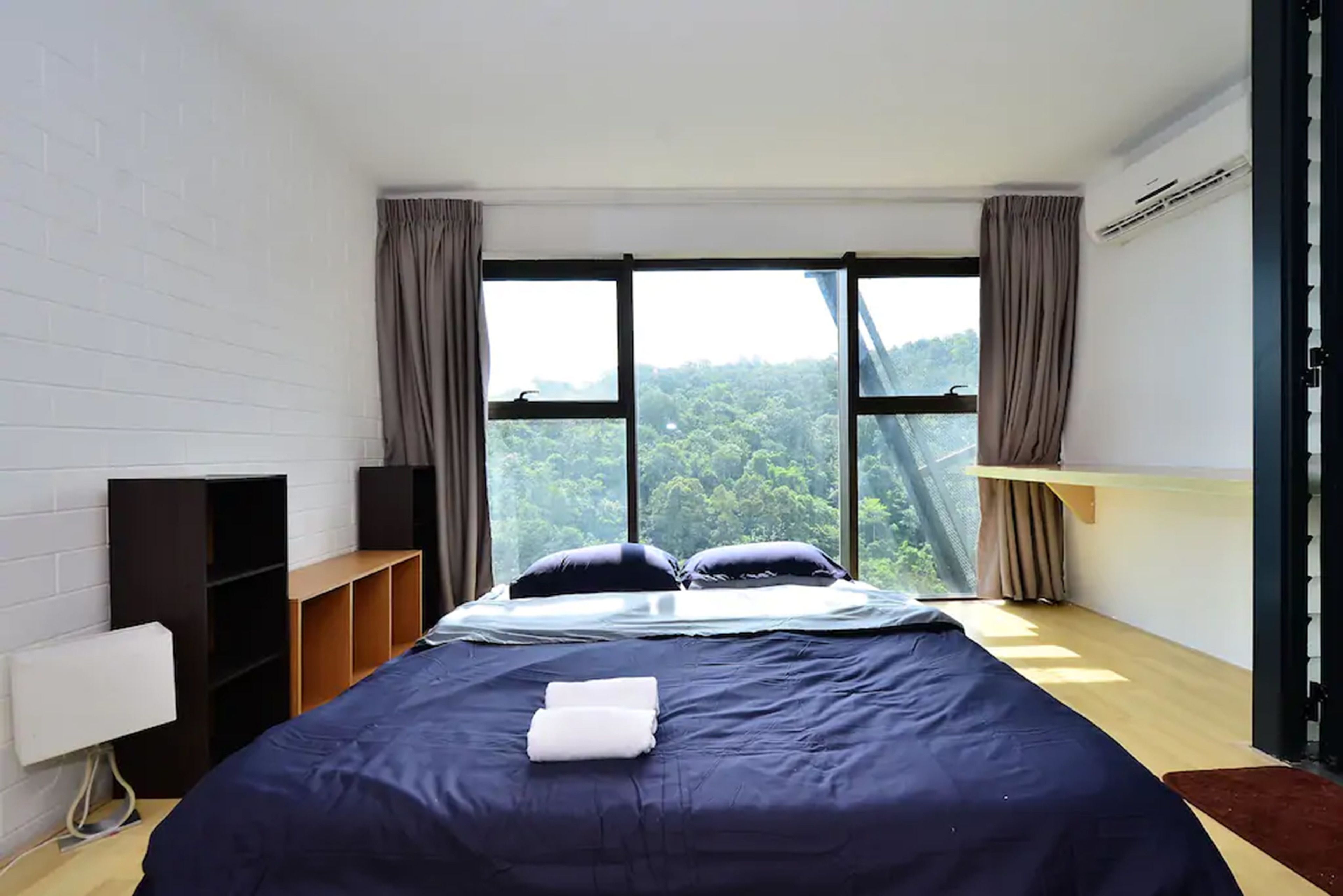 A modern hotel room with a large bed, a built-in shelf, a bedside table, and a window with curtains.