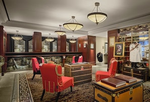 A formal room with a fireplace, red chairs, a display of military uniforms, and a collection of suitcases. - Maxwell Reserve Singapore, Autograph Collection (Singapore)