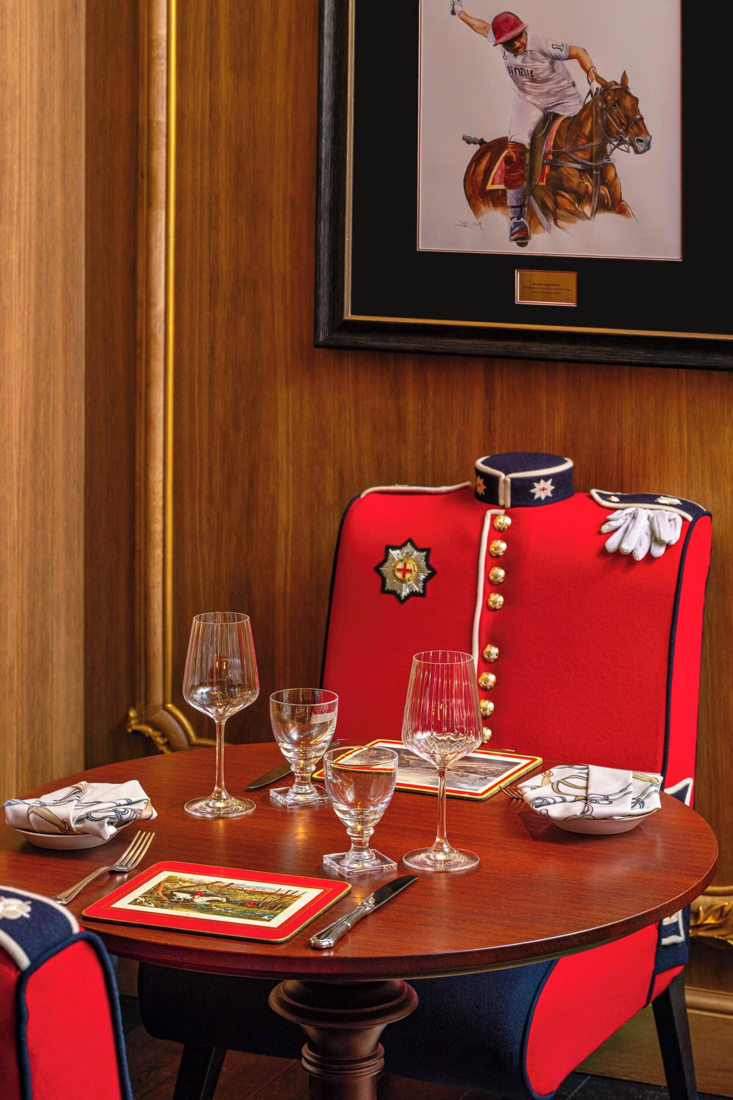 Una mesa de comedor dispuesta con copas de vino, un plato y un cuadro con la imagen de un jinete a caballo.