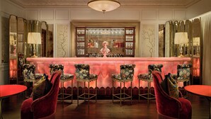 Un espace bar avec une table rouge, des tabourets de bar et un décor mural.