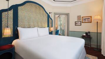 Ein Hotelzimmer mit einem großen Bett, einem Kopfteil mit dekorativem Muster, einem Nachttisch mit Lampe sowie einem kleinen Tisch und einem Bilderrahmen an der Wand.